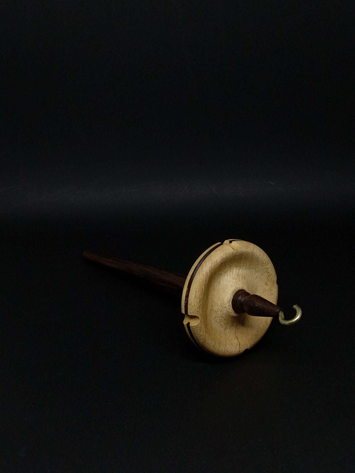 A spindle with a whorl that helps twist fibers into yarn. Held and dropped to create twist.