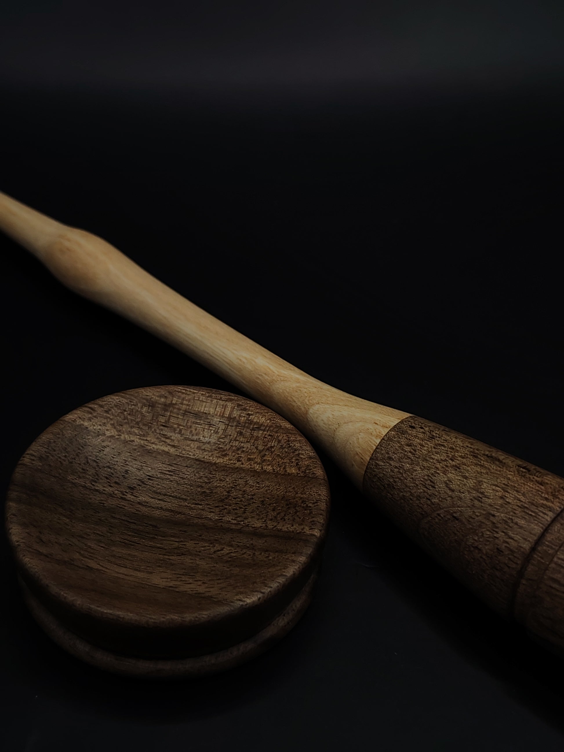 Close-up of chestnut shaft and carved walnut whorl on goddess spindle resting in bowl