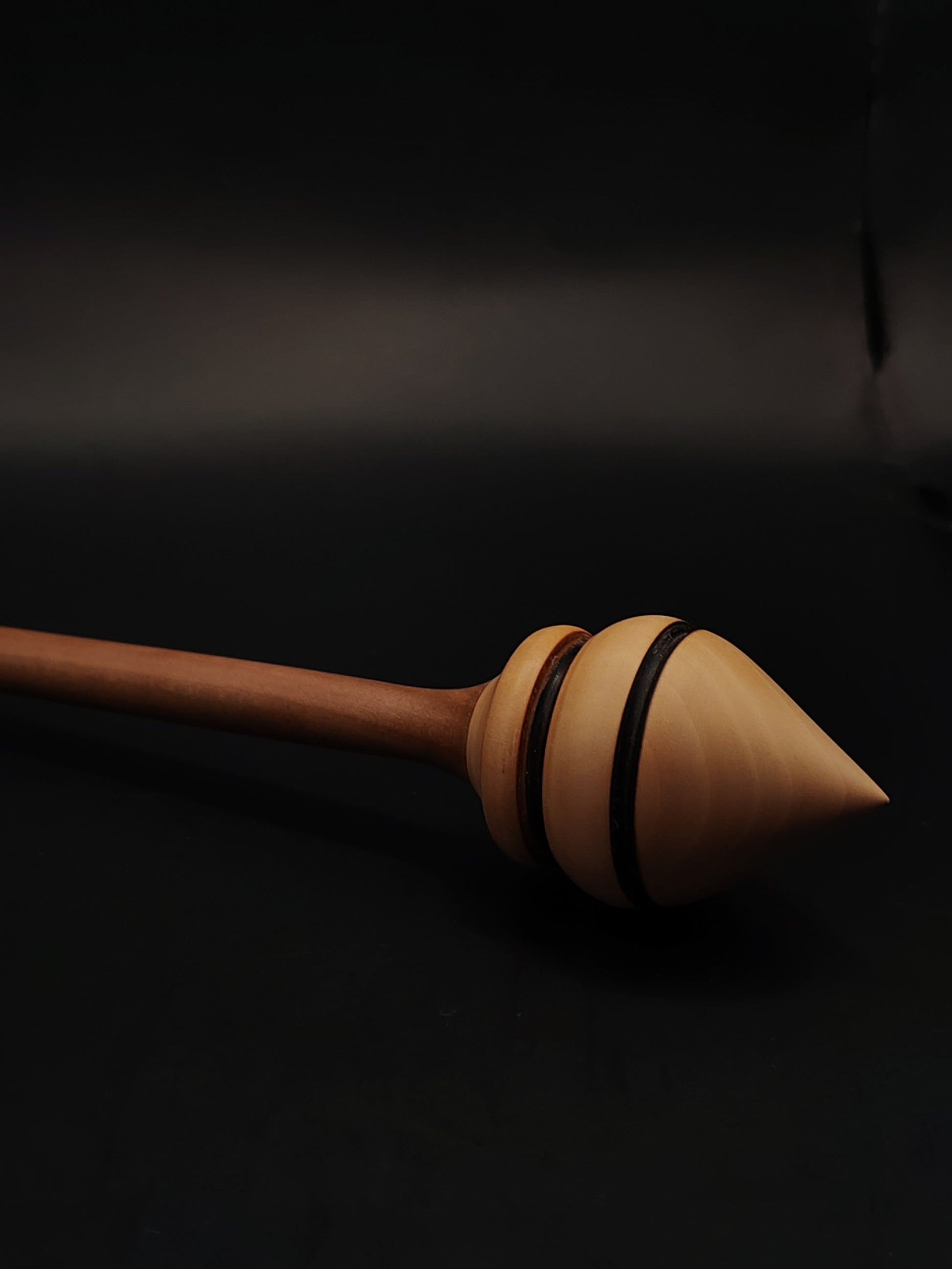 Close-up of support spindle’s pear whorl and plum shaft balanced in a beech bowl