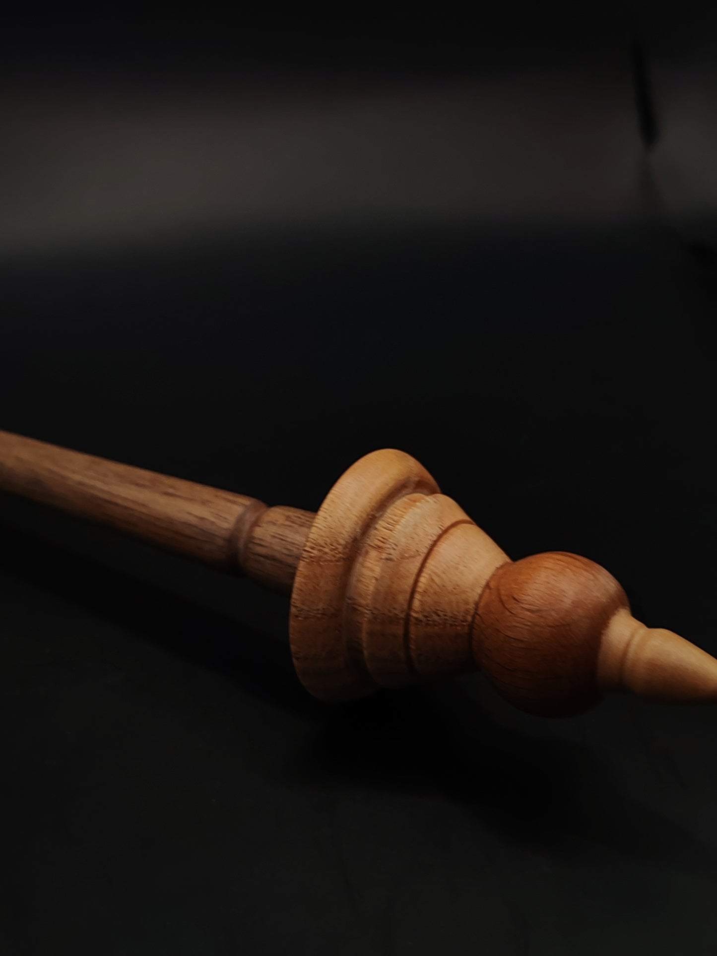 Side view of artisan spindle featuring walnut shaft and contrasting whorl design