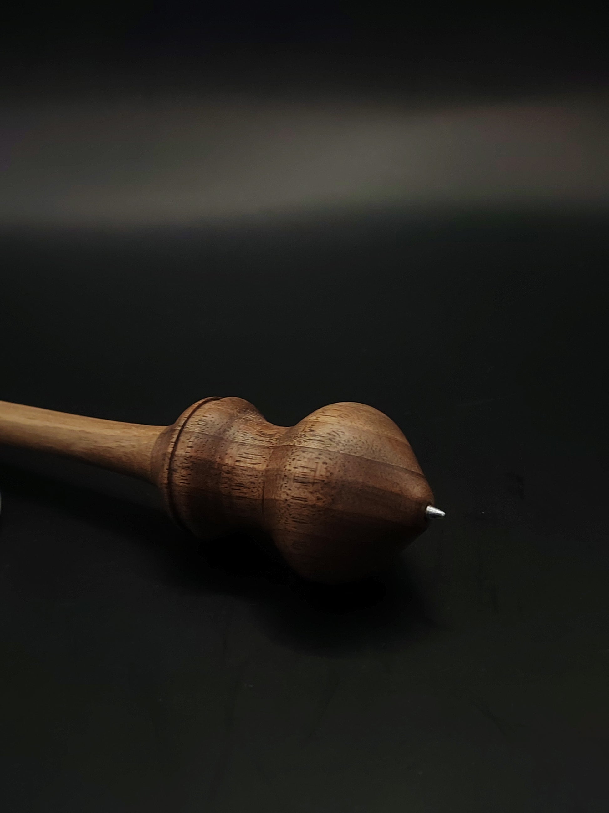 Side view of artisan support spindle with smooth walnut shaft and tapered metal tip