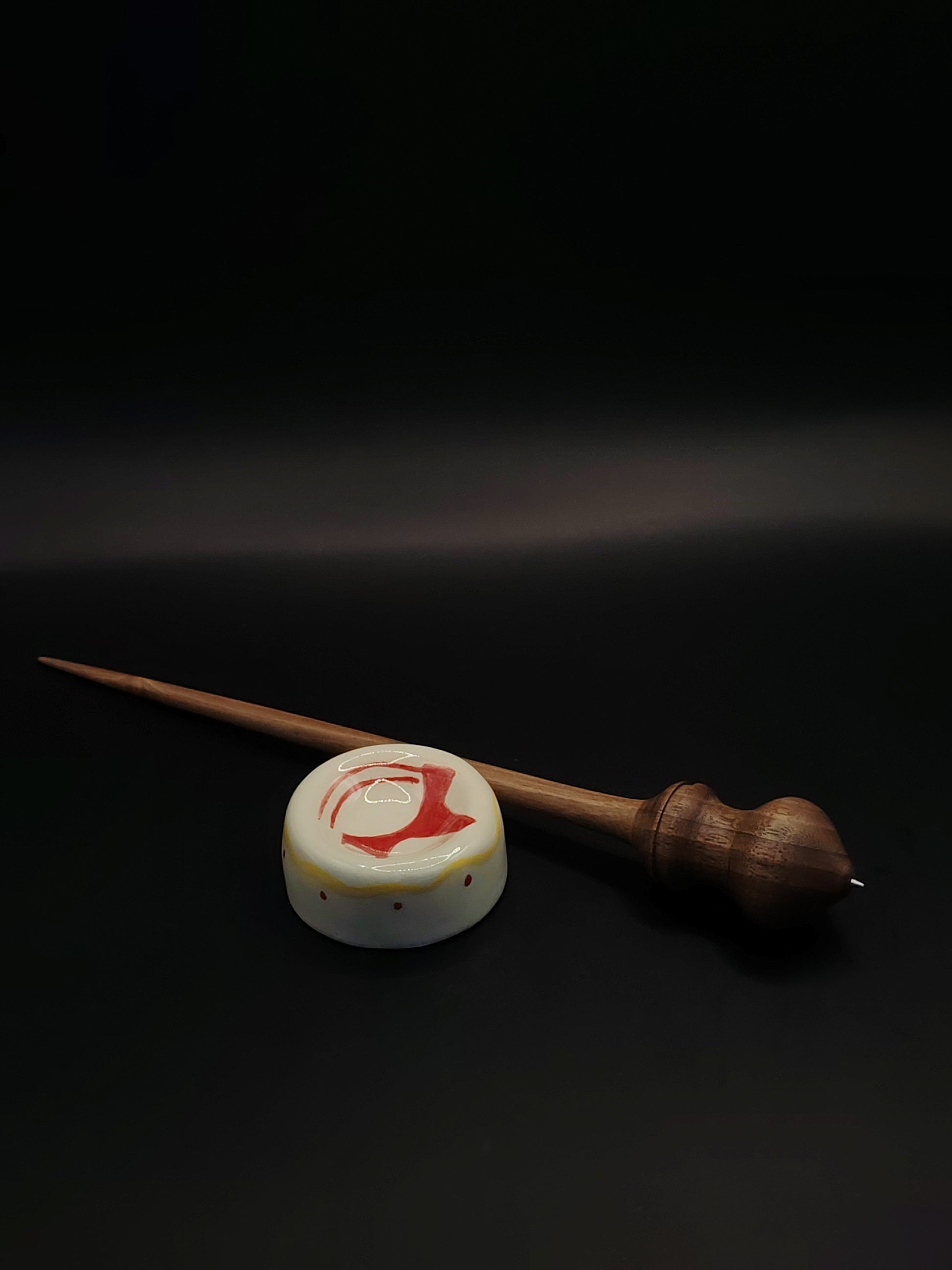 Close-up of walnut wood support spindle balanced in white ceramic bowl for spinning