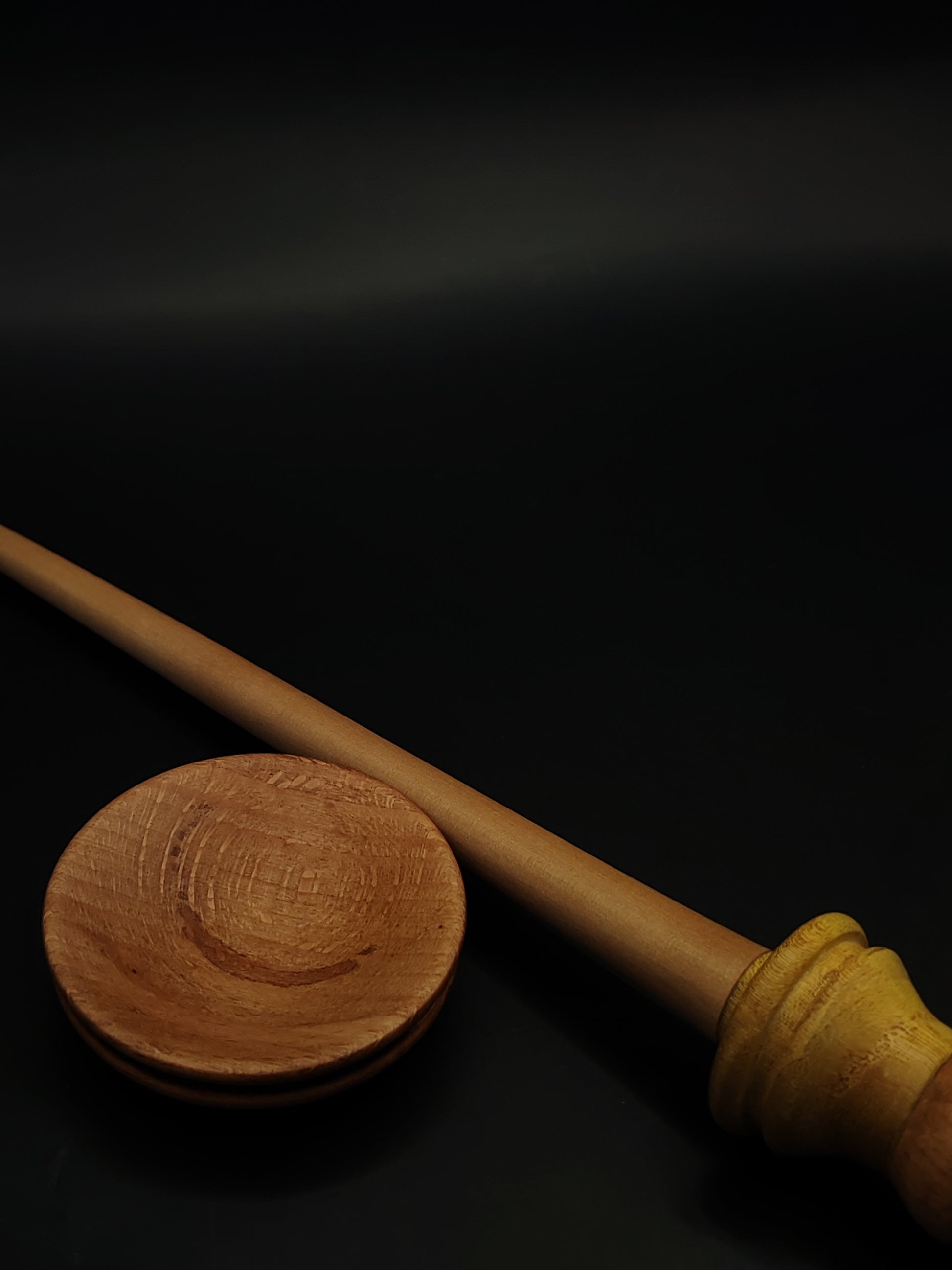 Close-up of apple and mulberry wood spindle resting in smooth beech support bowl