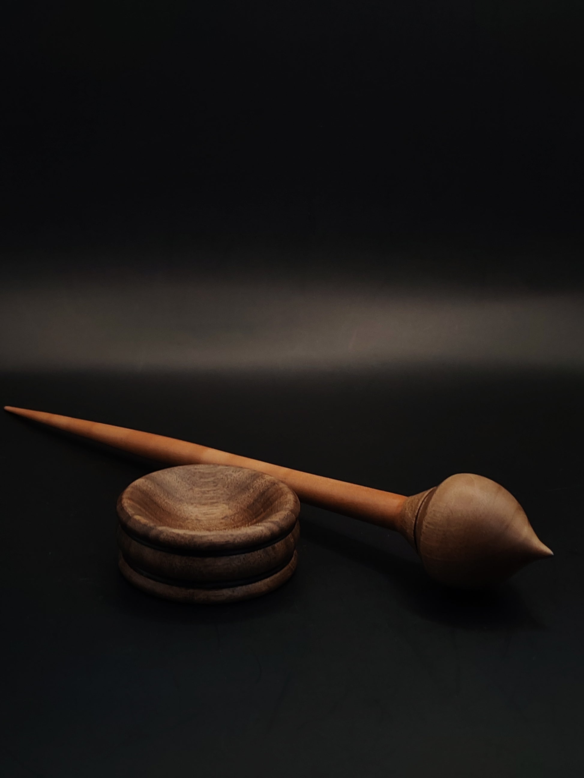 Handmade support spindle with plum wood shaft and walnut whorl, paired with walnut bowl