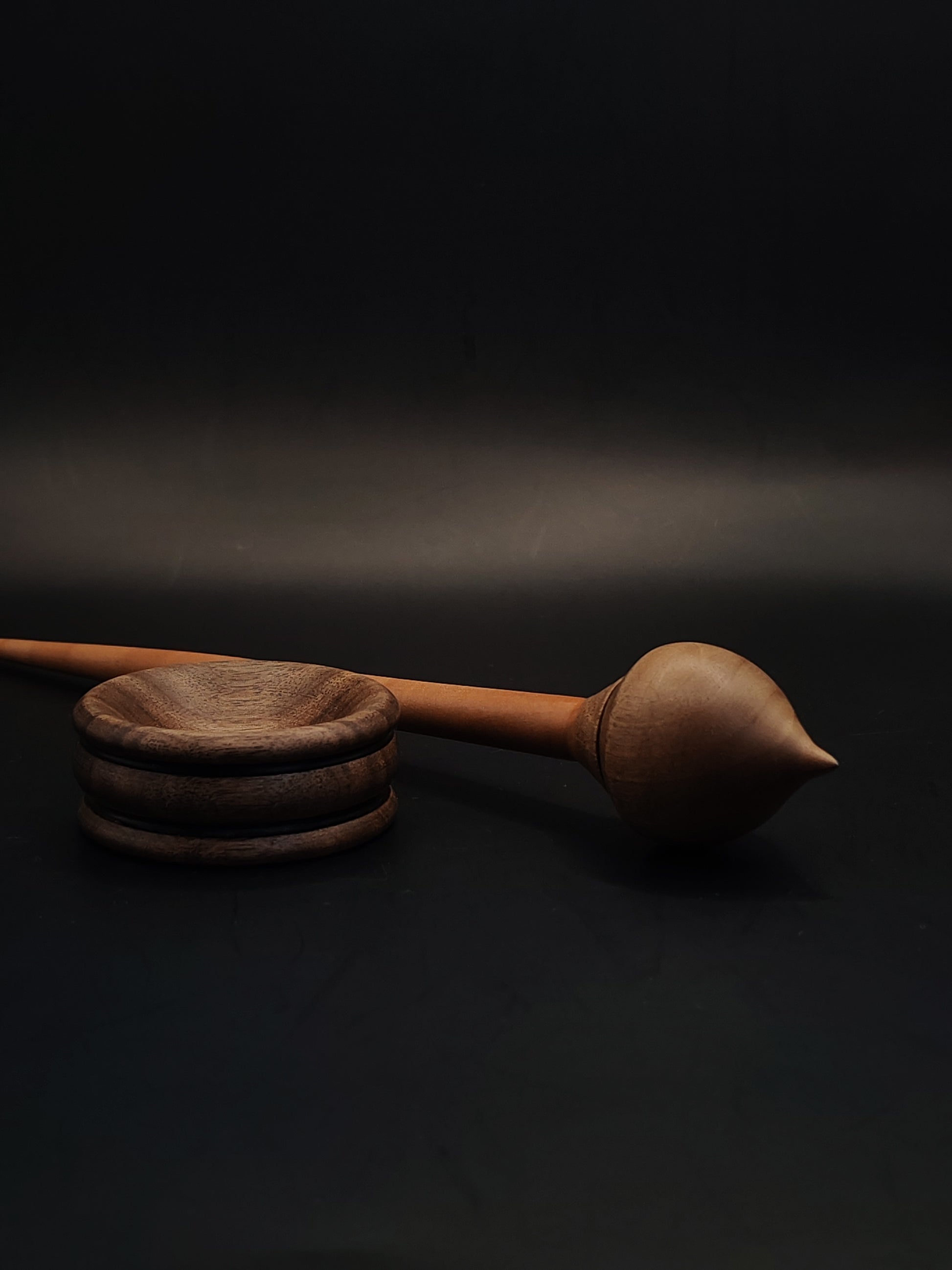 Side angle of artisan support spindle featuring plum shaft and smooth walnut whorl