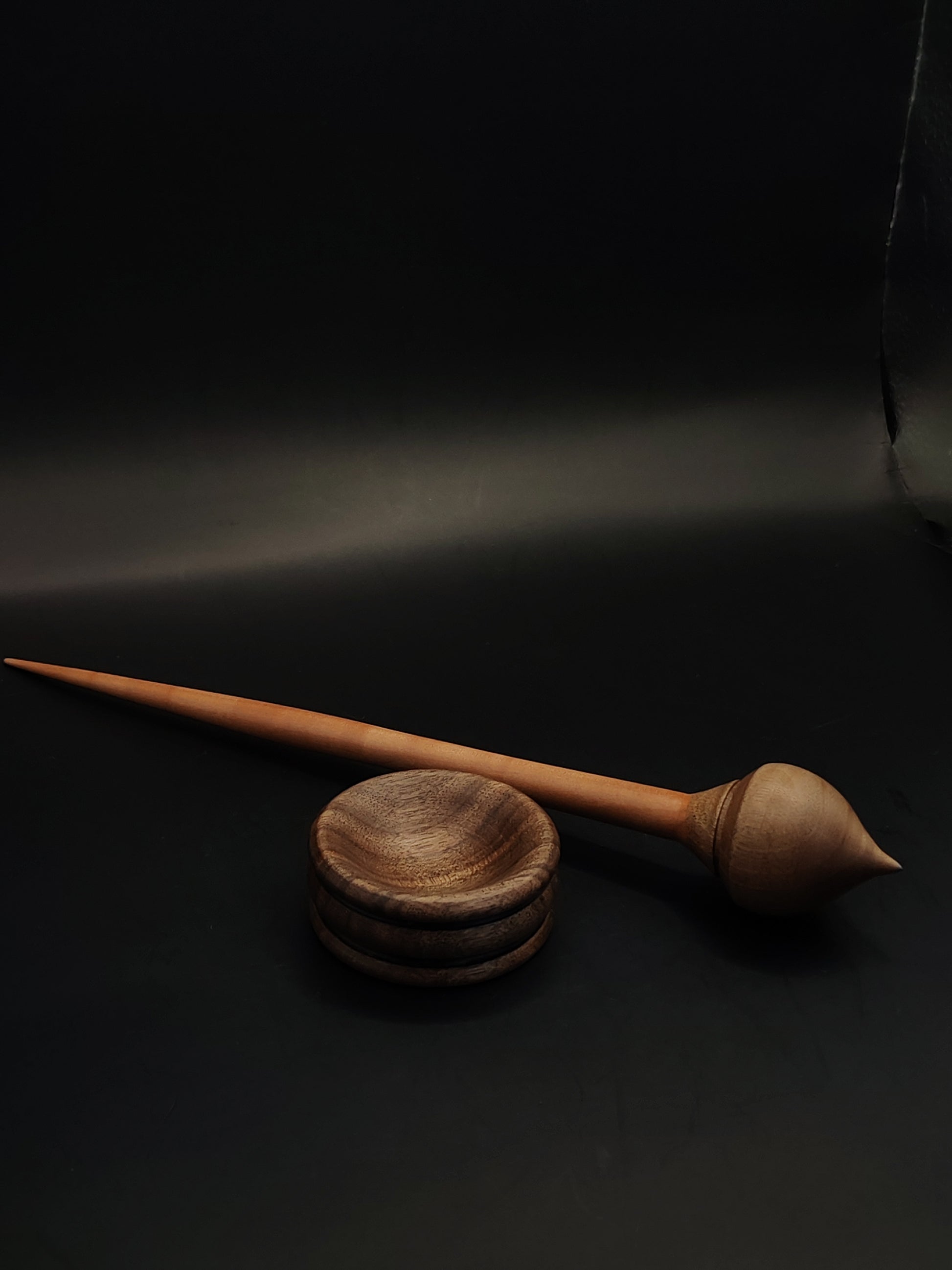 Plum and walnut wood support spindle resting in handcrafted walnut spinning bowl